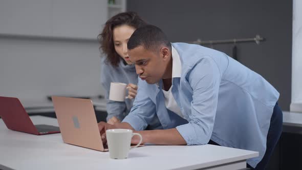 Creative African American Young Man Typing on Laptop Keyboard with Caucasian Woman Smiling Rejoicing