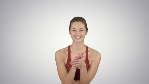 Beautiful young woman clapping and smiling on gradient background.