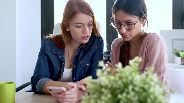 Slow motion shot of businesswomen using smartphone during meeting