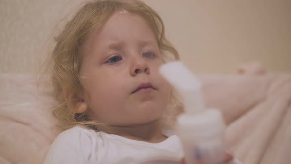 Upset Girl Undergoes Procedure with Modern Inhaler on Bed