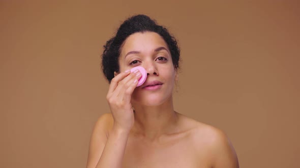 Beauty Portrait of Young African American Woman Cleansing Face with Pink Disc Removing Makeup