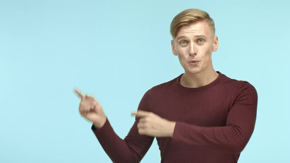 Attractive Young Man with Blond Short Hair Wearing Casual Shirt Pointing Fingers at Upper Left