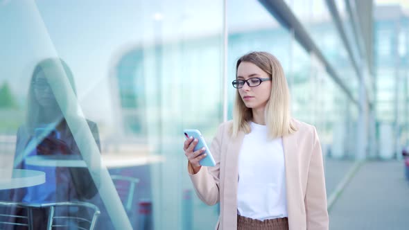 young business woman goes and uses mobile phone in her hands a urban 