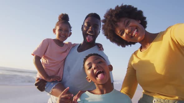 Portrait of smiling african american family looking at camera on sunny beach