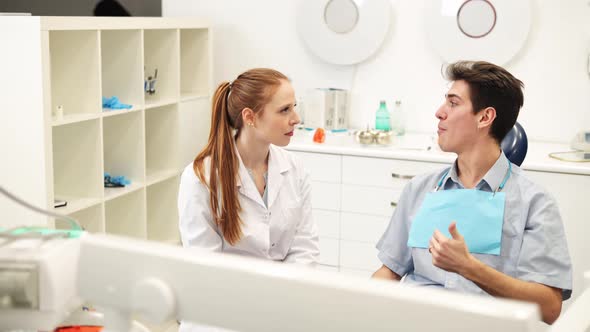 Young Empathic Female Dentist Listening to Male Patient Complaints During Dental Consultation