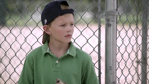 Slow motion of boy looking to the side as he hits his baseball mitt.