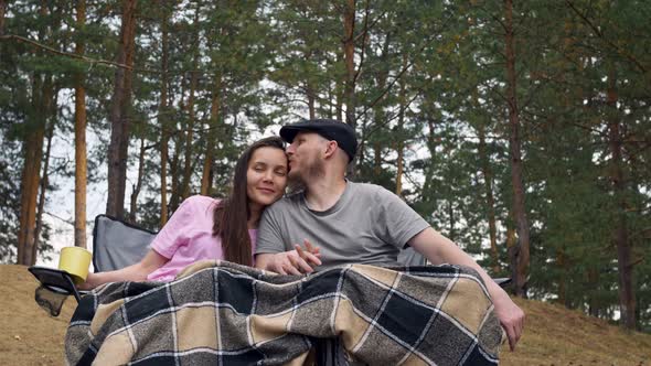 Couple in Love Husband and Wife Sit in the Woods on Folding Chairs for Camping Covered with Blankets