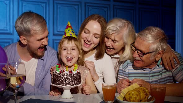 Girl Celebrating Birthday Party with Parents Senior Grandparents Family Blowing Out Candles on Cake