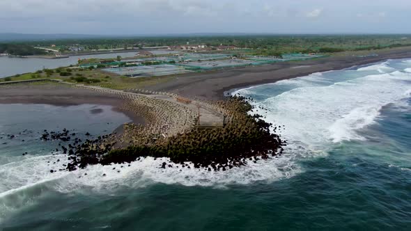 Oceanside pier and coastal salt ponds on Glagah Beach, Java, aerial arc shot