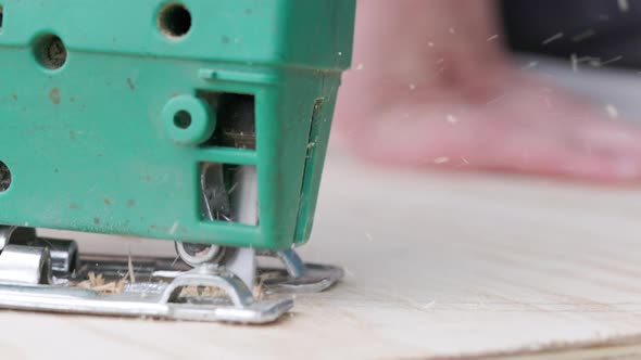 Sawdust Flies Off a Metal Blade As the Jigsaw Cuts Into a Sheet Plywood Workpiece