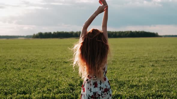 Carefree Redhaired Female Raising Arms Up and Dancing in Slow Motion. Happy Overjoyed Girl Whirling