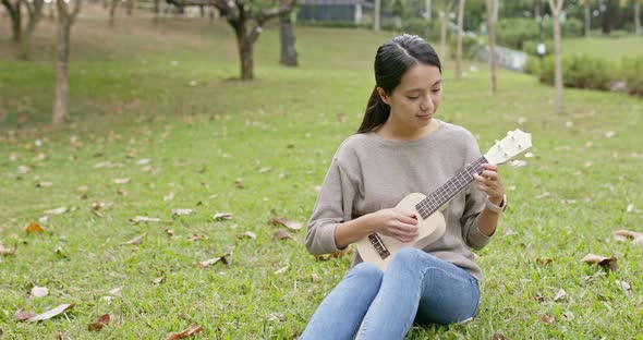 Woman play on ukulele at the park