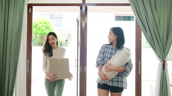 Happy asian women LGBT lesbian couple holding boxes entering new modern house