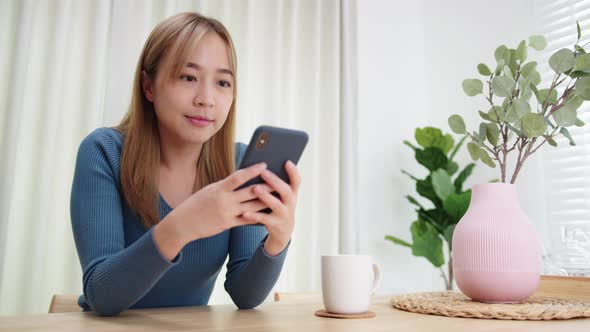 Young Asian Woman using mobile phone enjoying searching, surfing on the internet on a phone