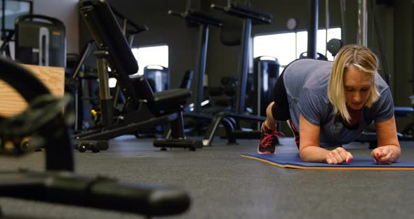 Senior woman doing plank in fitness studio 