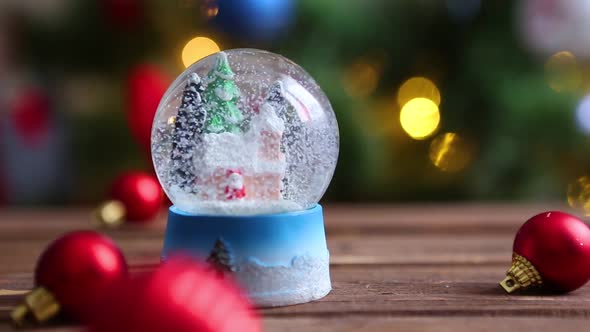 Christmas Snow Globe on Background of Christmas Tree with Christmas Lights