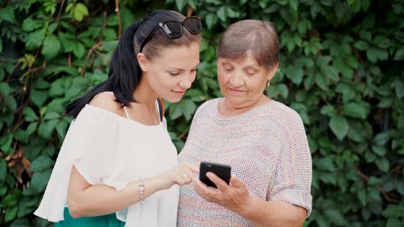 Granddaughter Shows Old Grandmother Something in Smartphone Teaches Her To Handle with Modern Gadget