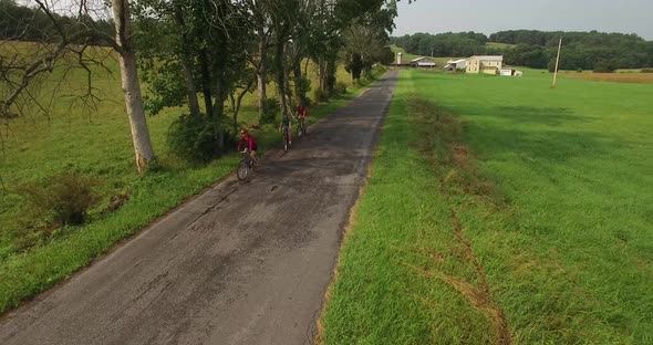 Aerial views of family bicycling along pastoral country roads.