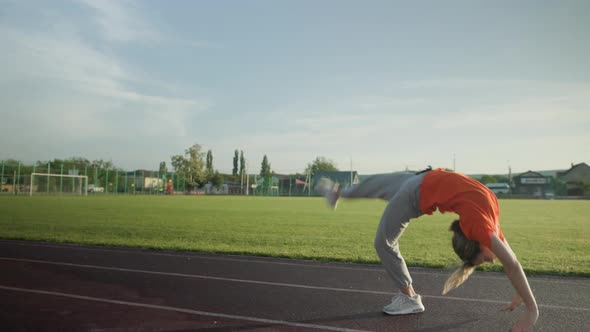 Young Beautiful Girl in Sweatpants and an Orange Tshirt Goes in for Sports