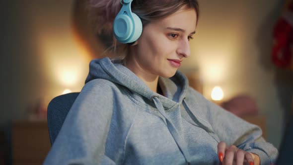 Laughing woman in headphones looking at laptop