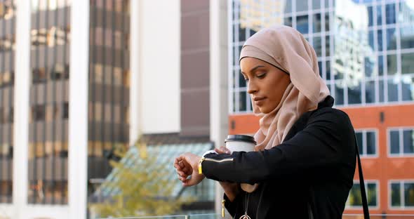 Side view of young Asian woman in hijab standing in the city 4k