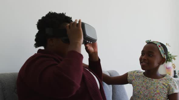 African american garndmother using vr headset sitting on the couch at home