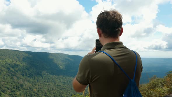 Back View of Blogger or Vlogger Recording Video or Shooting Photo on Smartphone