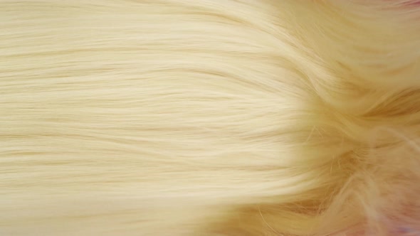 Slow motion of close-up of beautiful blond long smooth straight hair extension texture.