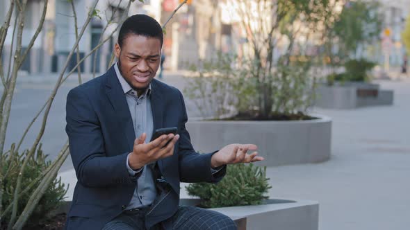 Mad Stressed Black Guy Holding Cellphone Annoyed with Error Spam Message Slow Stuck Broken