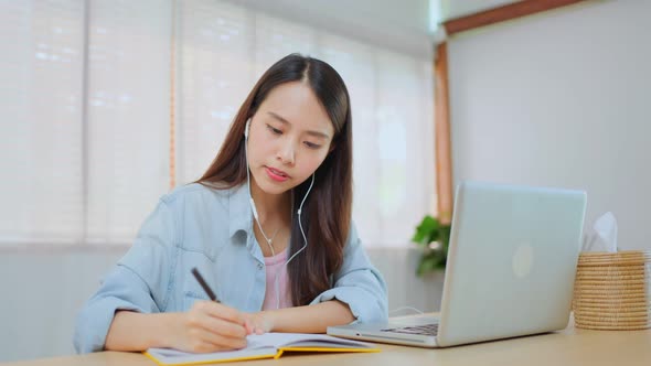 Distance learning of Asian Beautiful school girl study virtual online and writing in copy book.