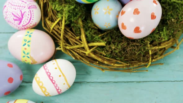 Painted Easter eggs in the nest on wooden surface