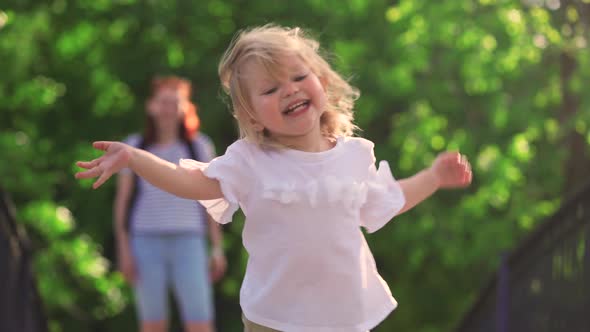 a two-year-old child runs in the park, runs to meet his parents alt