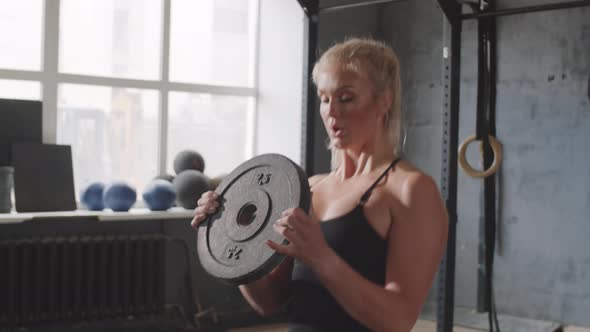 Sporty Woman Doing Lunges with Weight Plate in Gym alt