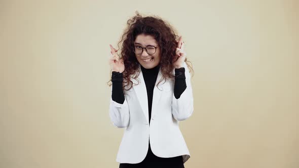 Successful Young Woman with Curly Hair with Crossed Fingers Makes a Wish