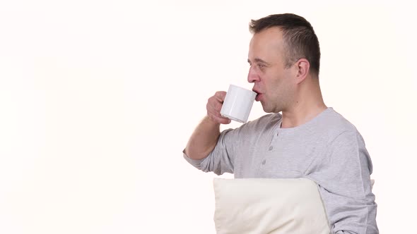 Man at Morning Holds Coffee Mug and Pillow