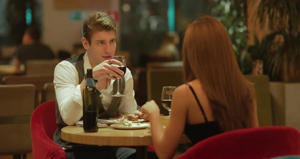 Young Handsome Man Eats in a Restaurant with a Beautiful Woman and Drinks Wine