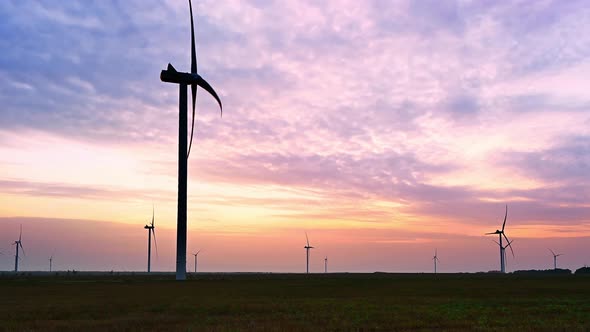 Wind turbine in an offshore wind farm in the green field against low sun on sunrise the close-up.