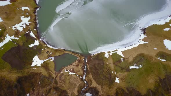 Abstract aerial view of waterfall and frozen lake in Iceland.