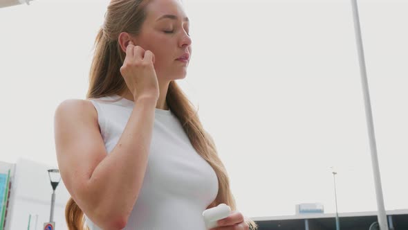 Slow motion young woman outdoor putting earphones on overlooking serene