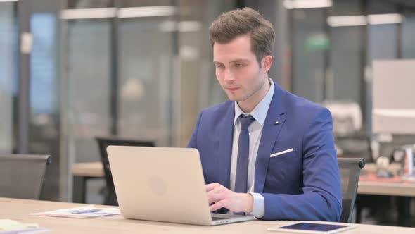 Businessman Shaking Head As No Sign While Using Laptop in Office