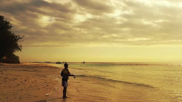 Fishing good looking boy on holiday hanging out at beach on paradise white sand and blue background 