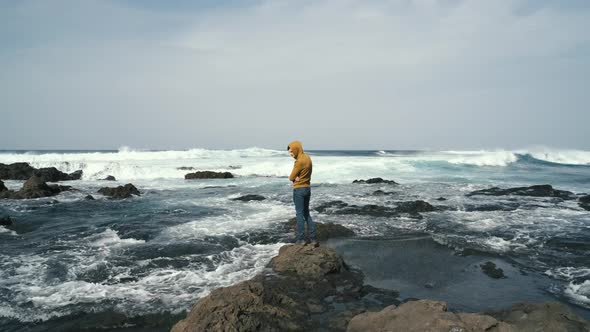 Tourist Man in Yellow Sweatshirt Walks on Volcanic Beach in North of Canary Island Tenerife