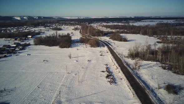 Aerial view of an asphalt road surrounded by snow