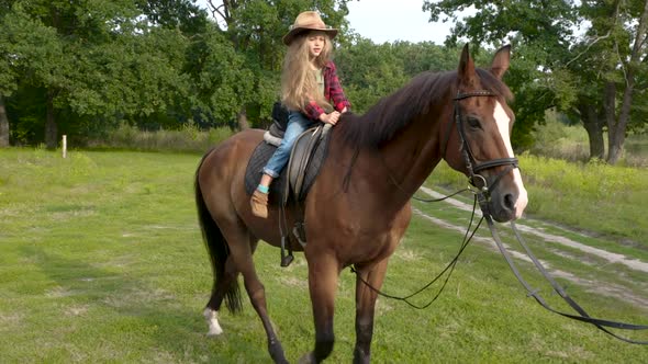 Young Cowgirl in Hat Riding Her Horse