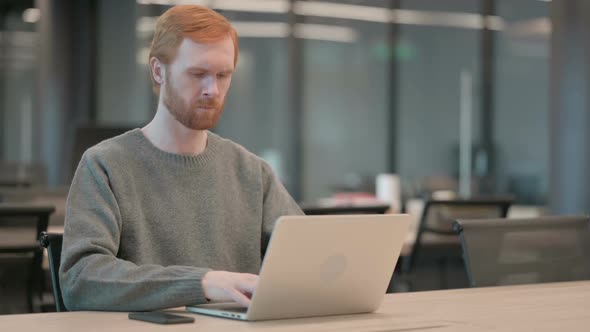 Young Man Coughing While Using Laptop in Office