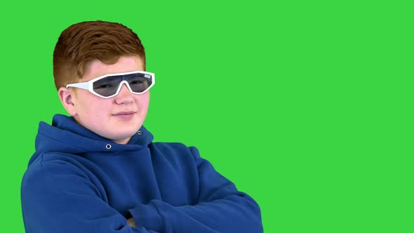 Teenager Kid Wearing Sunglasses Standing with Arms Crossed Convinced and Confident on a Green Screen