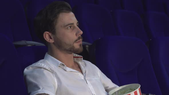 A Cute Guy Looks Closely at the Movie in the Cinema and Shows a Sign of Silence
