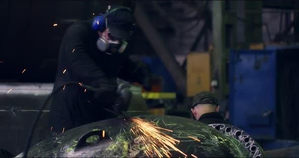 A Professional Worker in a Protective Mask Works with a Grinder in a Factory