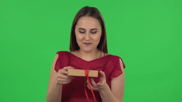 Portrait of Tender Girl in Red Dress Is Opening the Gift, Very Surprised and Upset. Green Screen