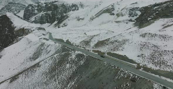 Aerial View Of Parked SUV On Desolate Winter Road Beside Snow Covered Landscape In Upper Hunza. Doll